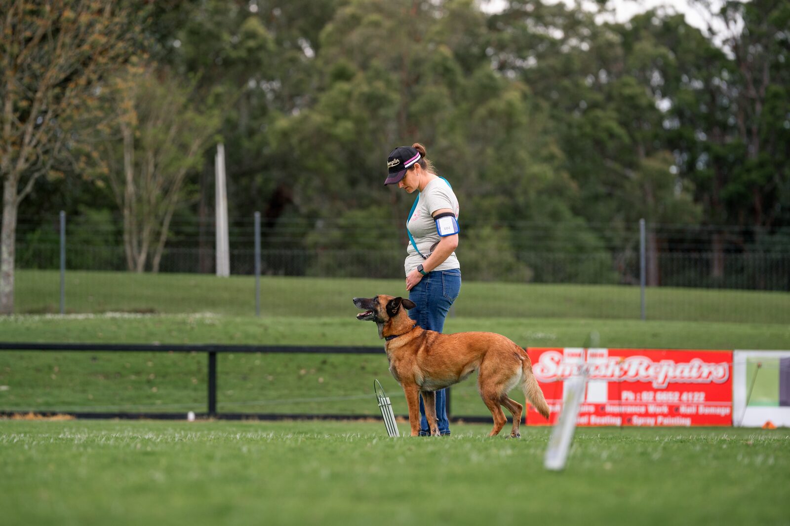 A dog and handler working together beside a Rally course sign